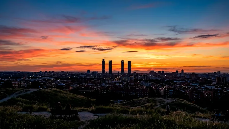 Madrid skyline with Cuatro Torres silhouetted under an orange sunset sky